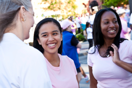 A middle aged lady talks to two teenage girls at a community event